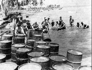 Australian troops on New Guinea gather invaluable drums of gasoline and lubricating oil dropped overboard from a ship. These supplies kept military vehicles in action.