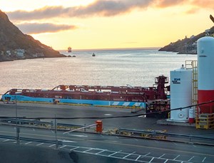 Fig. 1. As the sun comes up on another day, one workboat servicing Grand Banks installations is about to enter the channel to the Port of St. John’s, while another workboat at the A. Harvey docks takes on equipment and supplies, preparatory to making another run to Newfoundland’s producing facilities. Photo by the author.