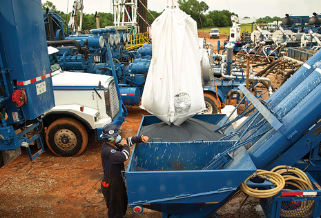 Ultra-lightweight proppant is poured into a hopper during hydraulic fracing of a Woodford Shale well. Its lower specific gravity, compared with conventional proppant, is associated with longer effective frac length. Courtesy of Baker Hughes.