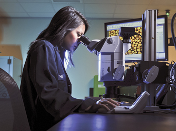 A CARBO research chemist examines a CARBOBOND RCS sample under a scanning electron microscope to evaluate grain-to-grain bonding and ensure an optimal resin coating process.